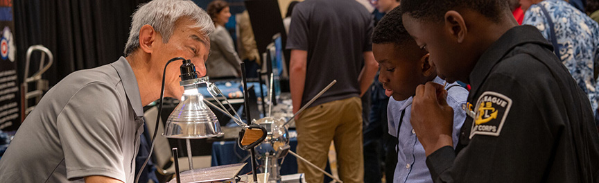 Sokhom Kith, an electronics engineer in NRL's Signal Identification Section, piques the interest of young minds at Navy League's 2023 STEM Expo. (U.S. Navy Photo)